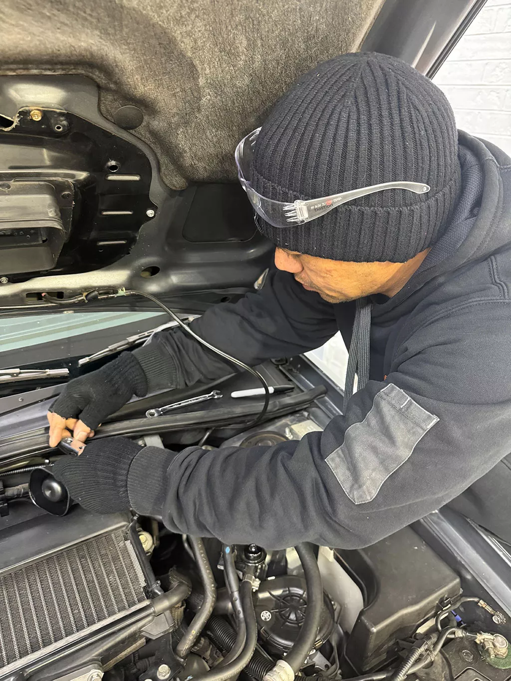 Two mechanics working under a vehicle bonnet