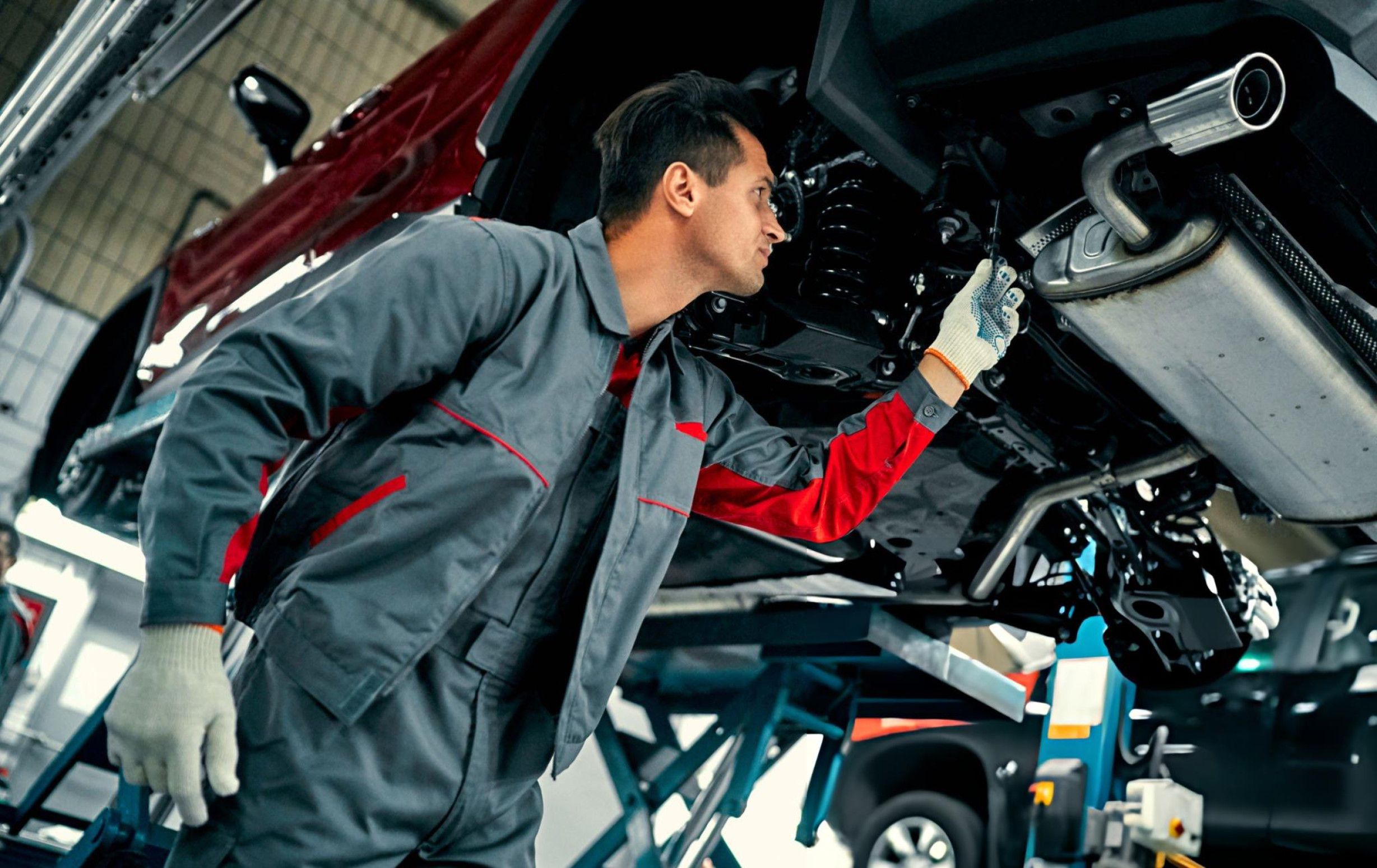 Mechanic working under a vehicle at Audio Visual Security workshop