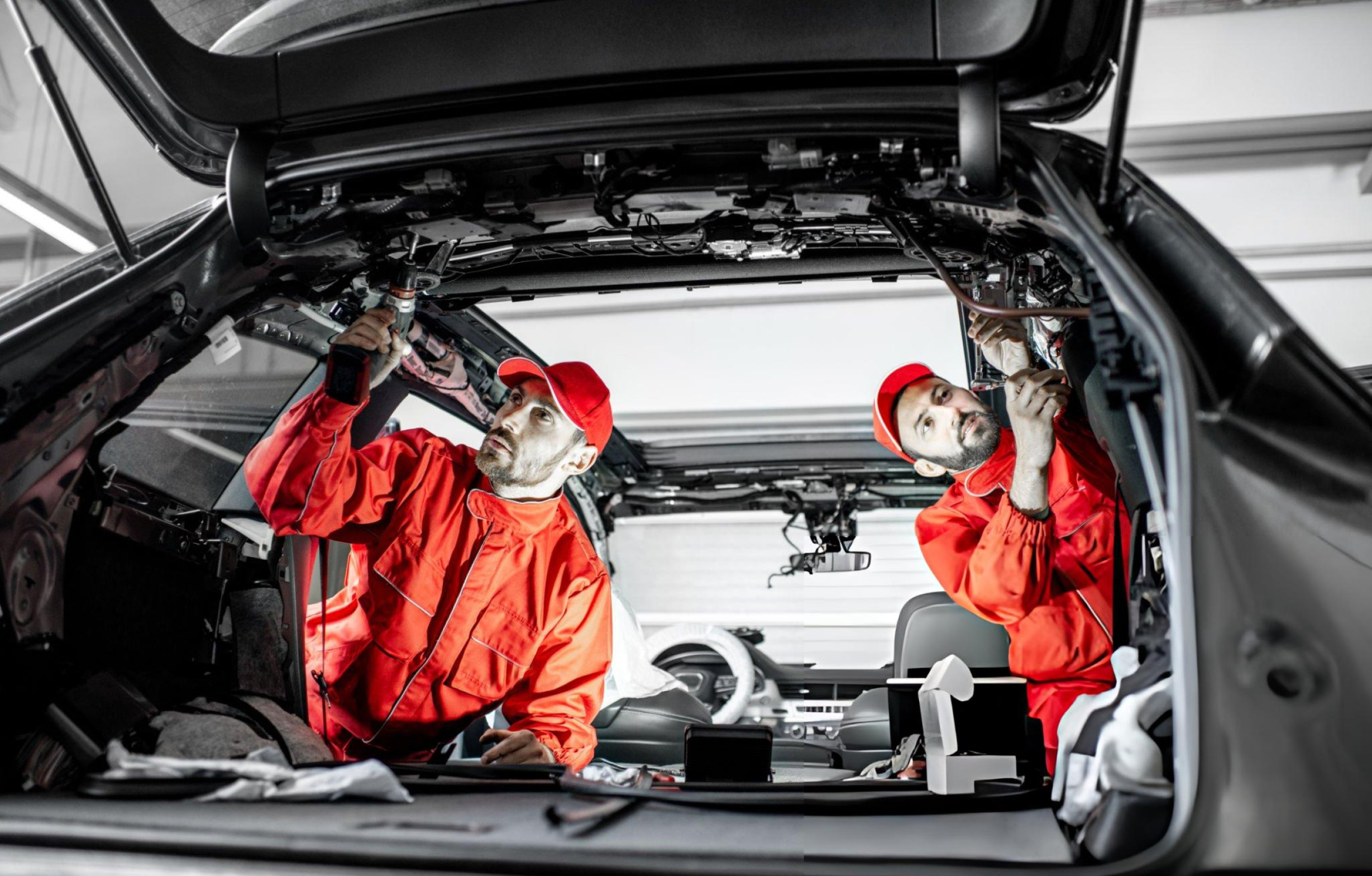 Two mechanics working under a vehicle bonnet